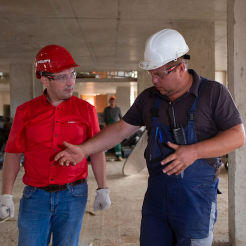 Deux hommes avec des casques discutent la rénovation d'un chantier.